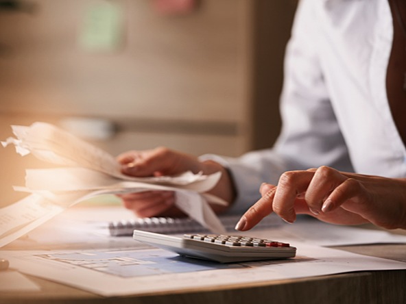 Image of business woman adding up figures on a calculator with a sheaf of papers in her hand